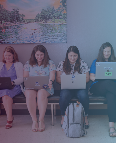 4 women sitting on a bench with laptops